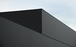 Detailansicht der Fassadenecke mit längsgeknickten Elementen in Sonderfarbton Regaliz 47 NP matt