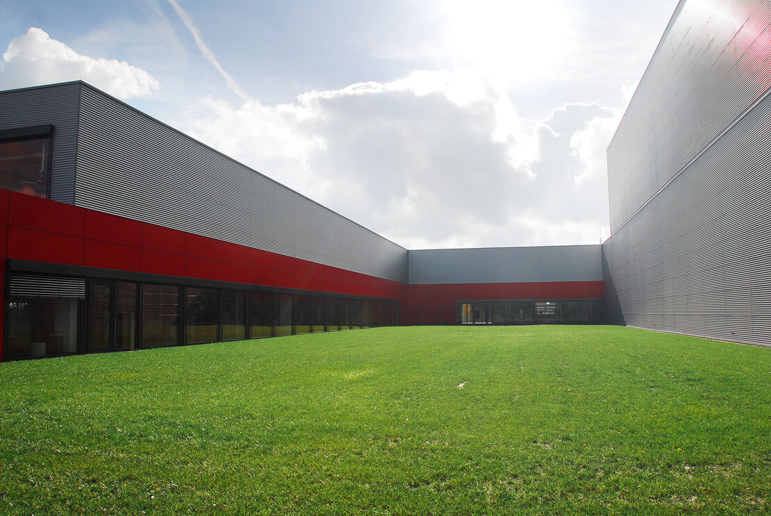 Produktionszentrum Waldenburg und Wellprofilen und roten Fassadenelementen