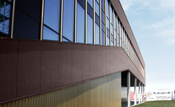 Fassade des Sportzentrums Augsburg mit Aluminiumtrapezprofil Typ 20-125 und Roma Sandwichpaneelen in Sonderfarbton Ice Crystal dark Brown Relief