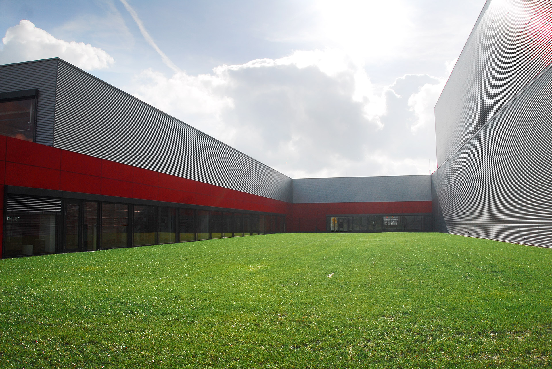 Produktionszentrum Waldenburg und Wellprofilen und roten Fassadenelementen